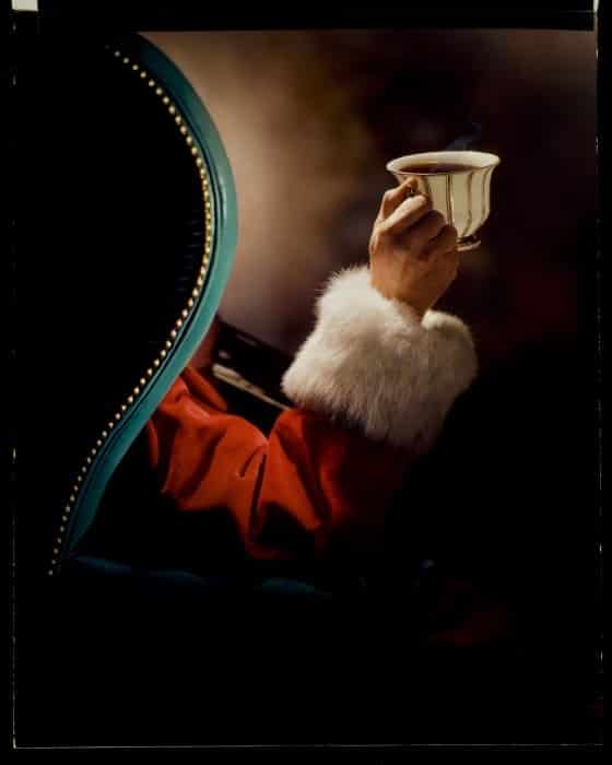 Santa holding a cup sitting in a chair